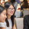 A color photo of three women sitting and smiling at the new majors welcome for Cornell Bowers CIS.